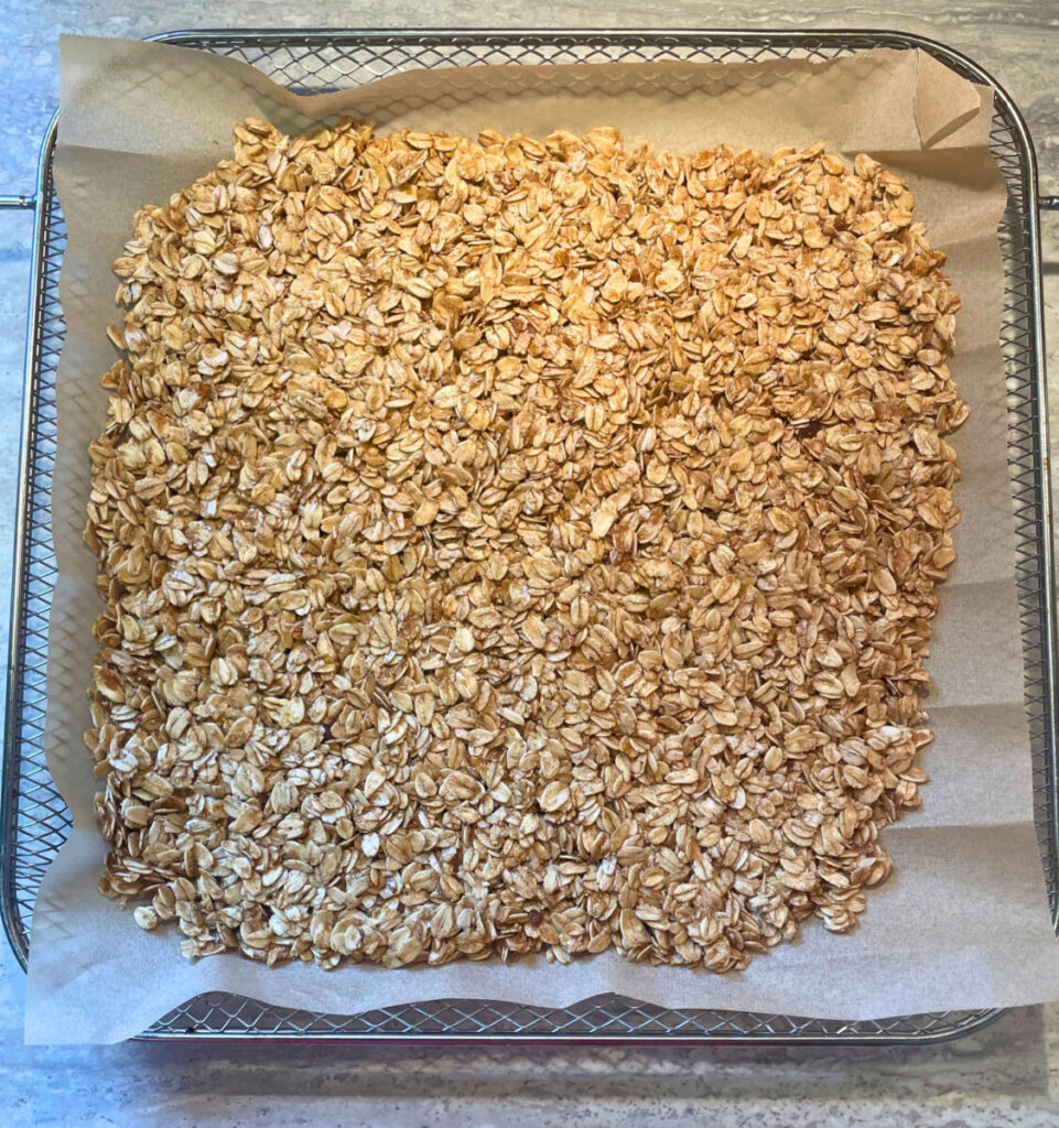 unbaked granola spread out on an air fryer tray
