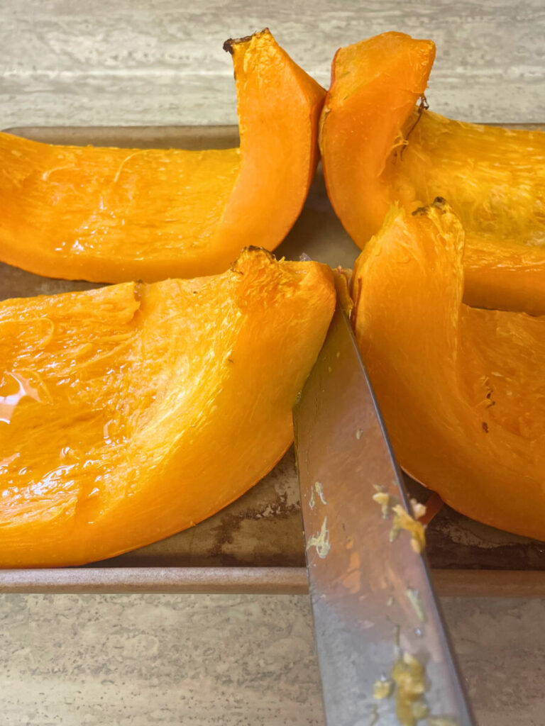 cooked pumpkin being cut with a knife