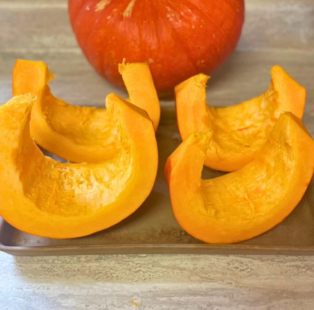 cut up pumpkin on a baking sheet