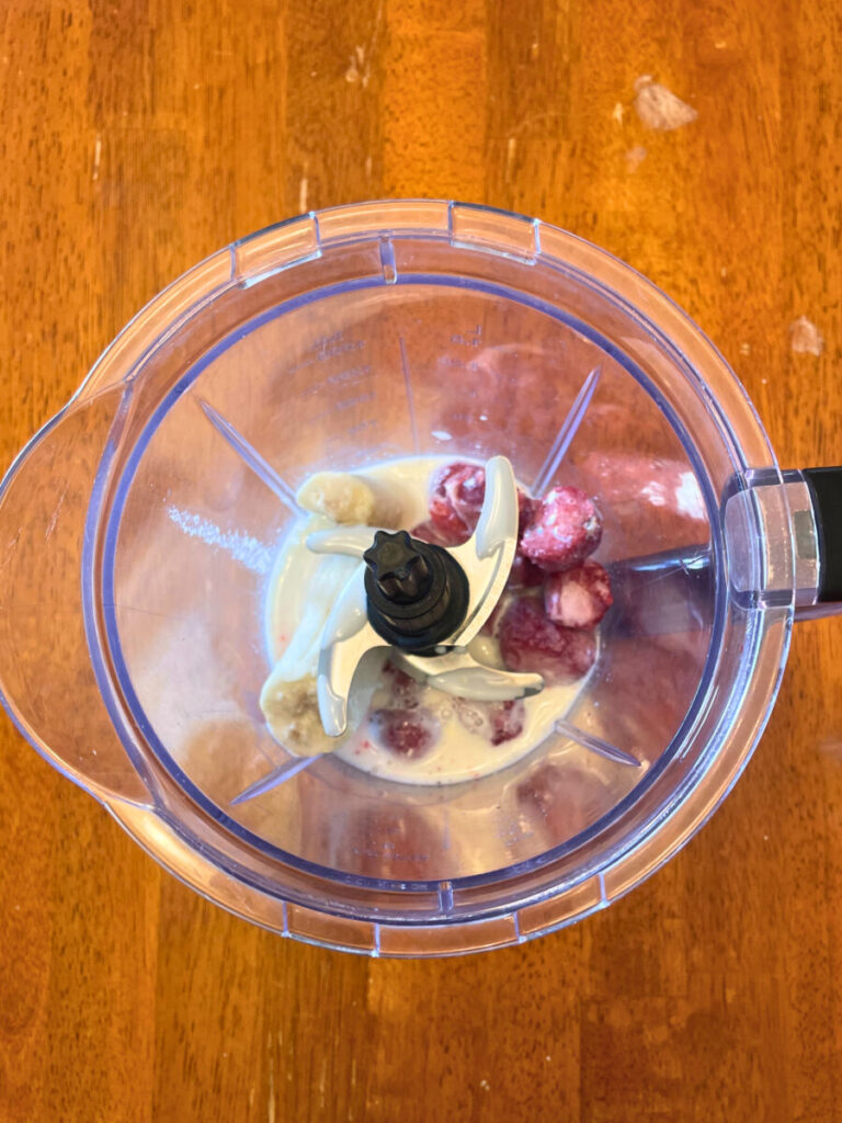 whole smoothie ingredients added to a blender