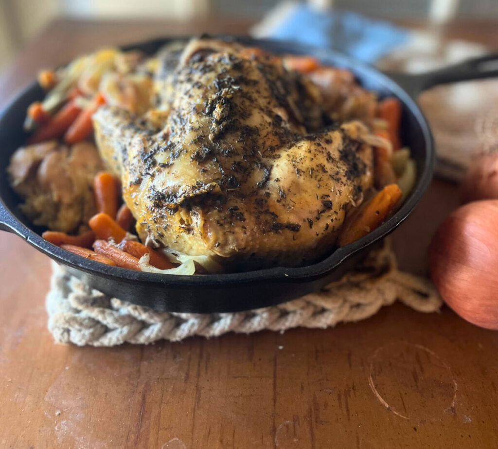 whole chicken in skillet with carrots