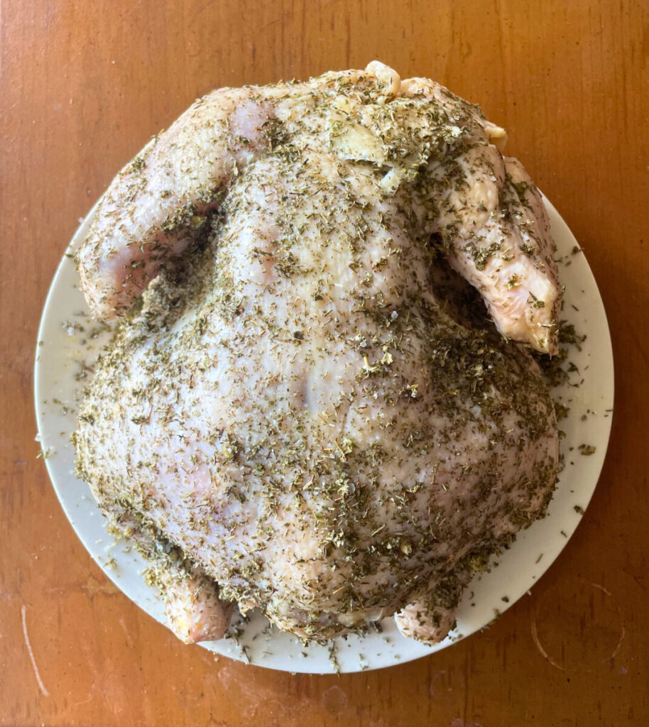 raw whole chicken coated in herb mixture