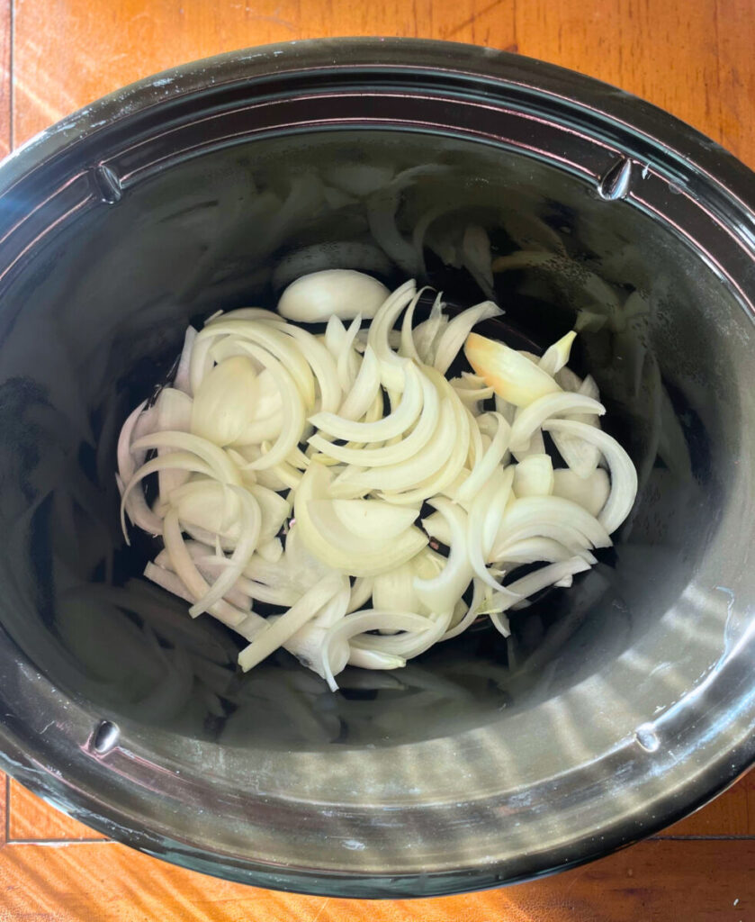 sliced onion in the bottom of a crockpot