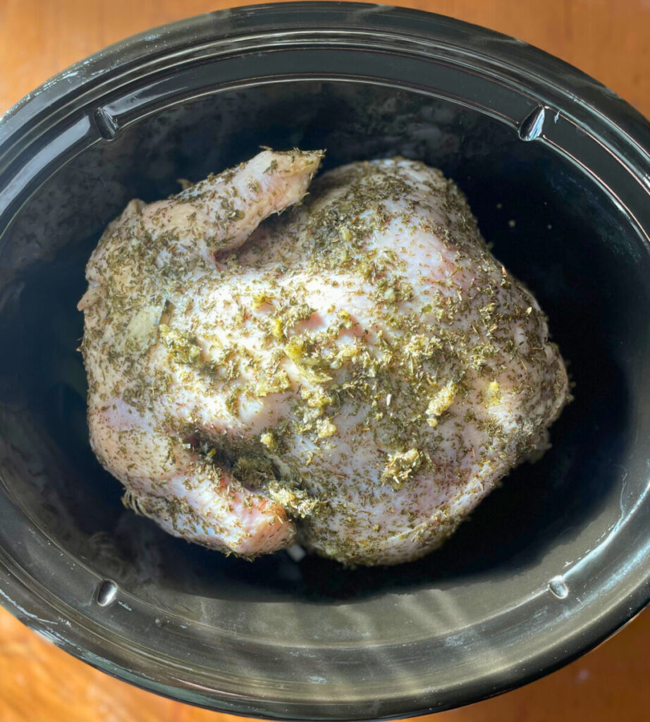 raw chicken coated in herb mixture placed in crockpot