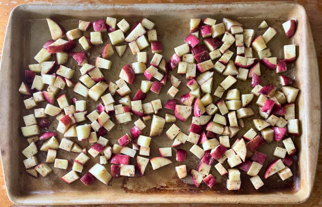diced raw red potatoes laid out on a baking stone