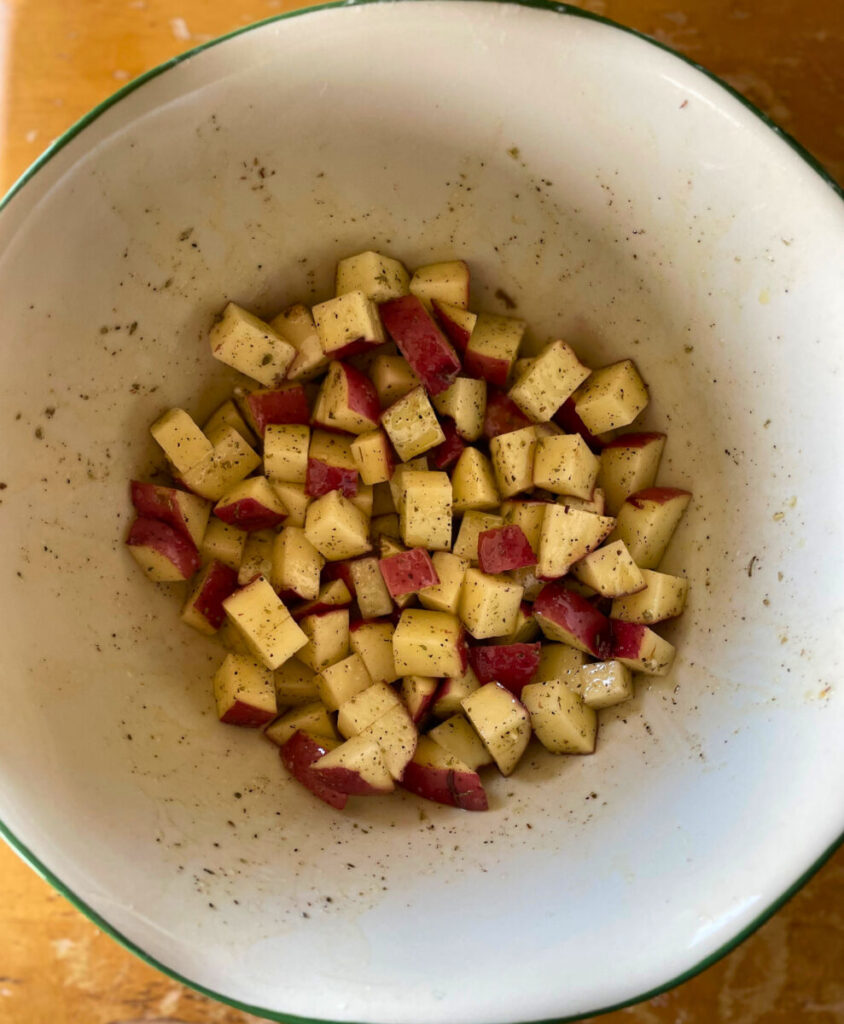 diced raw red potatoes in a bowl with seasonings and oil